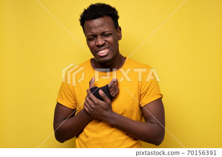 Young african american man holding his hand having pain in wrist Young african american man holding his hand having pain in wrist 70156391