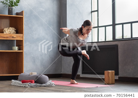Young woman practicing yoga, standing in Eagle exercise, Garudasana pose 70156441