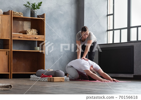 Caucasian female yoga teacher helping to stretch muscles her student. Caucasian female yoga teacher helping to stretch muscles her student. 70156618