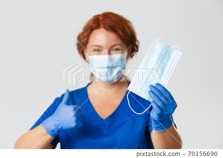 Medical workers, covid-19 pandemic, coronavirus concept. Close-up of professional female nurse, doctor recommend wearing face masks and protecting equipment to prevent virus outbreak, thumb-up 70156690