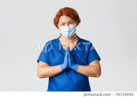 Medical workers, covid-19 pandemic, coronavirus concept. Distressed begging redhead female doctor in face mask and rubber gloves pleading, supplicating, cry for help, grey background Medical workers, covid-19 pandemic, coronavirus concept. Distressed begging redhead female doctor in face mask and rubber gloves pleading, supplicating, cry for help, grey background 70156692