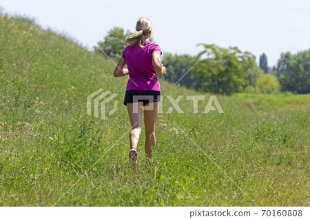 Young woman running in nature on a rural road Young woman running in nature on a rural road 70160808