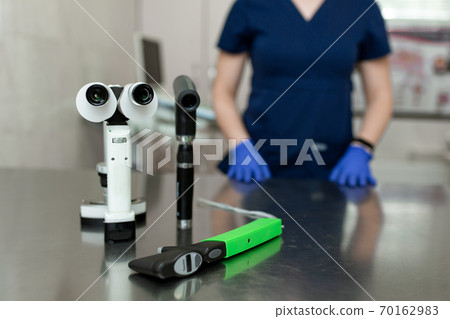 Professional equipment of a veterinary doctor ophthalmologist - manual slit lamp, ophthalmoscope, veterinary tonometer. Blurred Background 70162983
