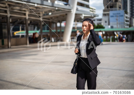 woman walking ang headache about business problem in city 70163086
