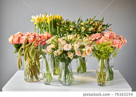 Many different colors on the stand or wooden table in the flower shop. Showcase. Background of mix of flowers. Beautiful flowers for catalog or online store. 70163254