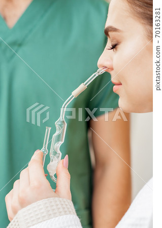 Young woman receives nasal inhalation. 70163281