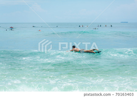 The guy is swimming on the surf board on the ocean. Healthy active lifestyle in summer vocation. 70163403