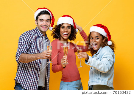 Three excited diverse friends celebrating Christmas drinking champagne together Three excited diverse friends celebrating Christmas drinking champagne together 70163422