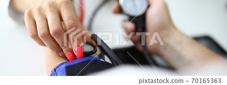 Woman's hand holds tonometer and measures patient's pressure. Woman's hand holds tonometer and measures patient's pressure. 70165363