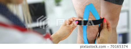 Fixation of kinesio tape on the patient's leg. Fixation of kinesio tape on the patient's leg. 70165374