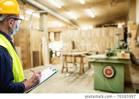 Engineer at work protects the face with the surgical mask. Construction industry. Covid19 prevention Engineer at work protects the face with the surgical mask. Construction industry. Covid19 prevention 70165897
