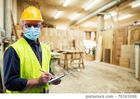 Engineer at work protects the face with the surgical mask. Construction industry. Covid19 prevention Engineer at work protects the face with the surgical mask. Construction industry. Covid19 prevention 70165898