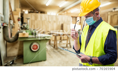 Engineer at work protects the face with the surgical mask. Construction industry. Covid19 prevention Engineer at work protects the face with the surgical mask. Construction industry. Covid19 prevention 70165904