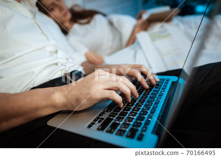 Young businessman is typing on laptop in bedroom. Young businessman is typing on laptop in bedroom. 70166495