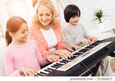 Lovely elderly woman teaches small grandchildren. 70166627