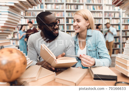 Ethnic African guy and girl surrounded by books. Ethnic African guy and girl surrounded by books. 70166633