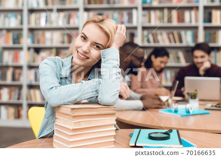Blonde smiling while sitting at a table in library 70166635
