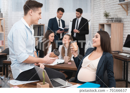 Pregnant girl in office is drinking coffee. Pregnant girl in office is drinking coffee. 70166637