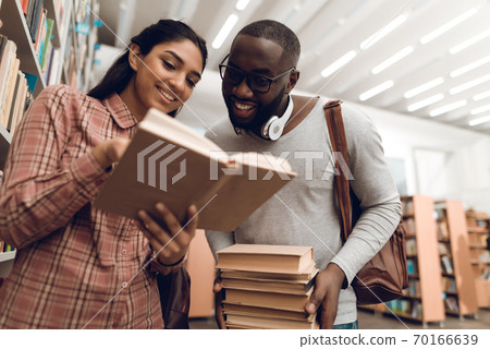 Woman shows something to a man with books. Woman shows something to a man with books. 70166639