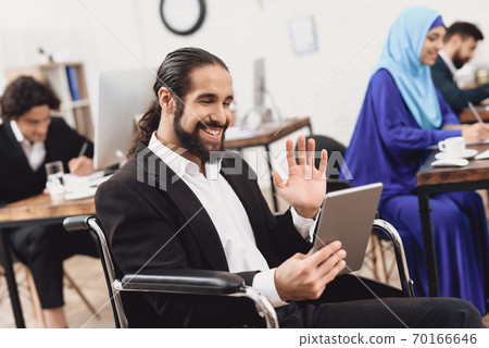 Disabled arab man in wheelchair working in office. Disabled arab man in wheelchair working in office. 70166646