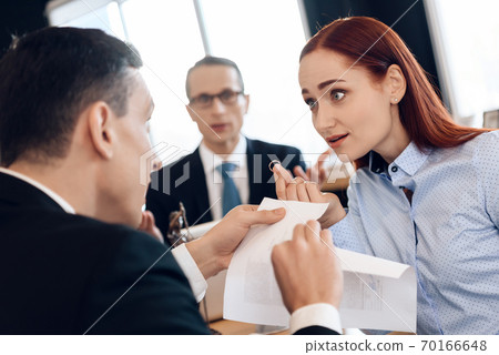 A woman looks at a man who is tearing a document. 70166648