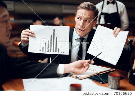 People gathered at a table in a restaurant. People gathered at a table in a restaurant. 70166650
