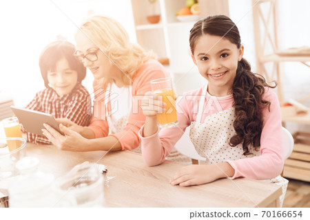 Girl sits at table and holds juice in her hands. Girl sits at table and holds juice in her hands. 70166654