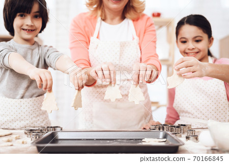 Grandmother with grandchildren shows cookie. Grandmother with grandchildren shows cookie. 70166845