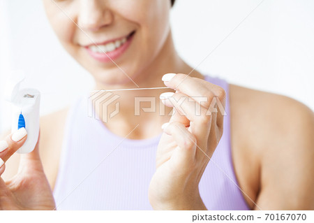 Portrait of beautiful woman cleaning teeth with dental floss 70167070
