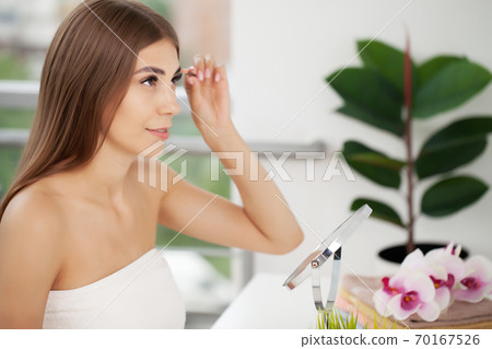 Young beautiful woman applying mascara makeup on eyes by brush 70167526