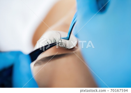Eyelash Extension Procedure, Professional stylist lengthening female lashes. 70167594