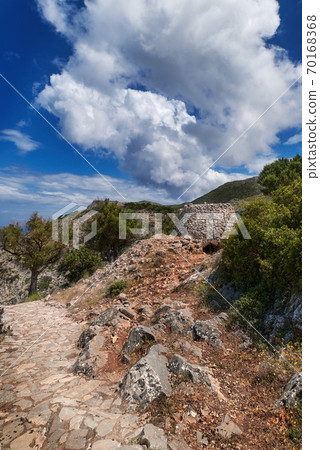 Greek or Cretan landscape, hills with spring foliage, bushes, olive trees, rocky path, mitato. Blue sky with clouds. Akrotiri, Chania, Crete, Greece 70168368