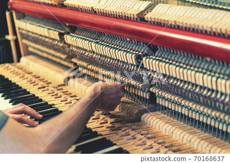 Piano tuning process. closeup of hand and tools of tuner working on grand piano. Detailed view of Upright Piano during a tuning. toned Piano tuning process. closeup of hand and tools of tuner working on grand piano. Detailed view of Upright Piano during a tuning. toned 70168637