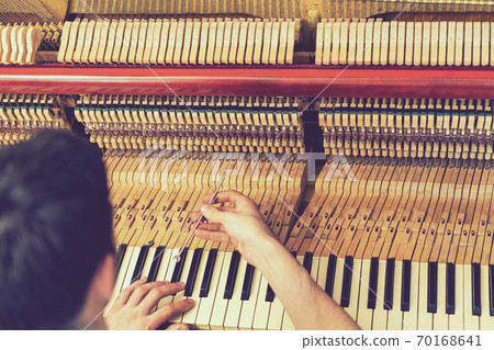 Piano tuning process. closeup of hand and tools of tuner working on grand piano. Detailed view of Upright Piano during a tuning. toned Piano tuning process. closeup of hand and tools of tuner working on grand piano. Detailed view of Upright Piano during a tuning. toned 70168641