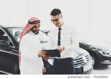 The consultant shows price of car to an Arab man. 70168982