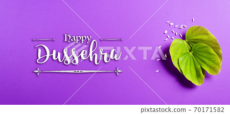 Happy Dussehra. Green leaf and rice on purple pastel background. Dussehra Indian Festival concept. 70171582