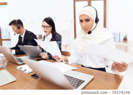 Girl in headphones sits and works in a call center Girl in headphones sits and works in a call center 70174248