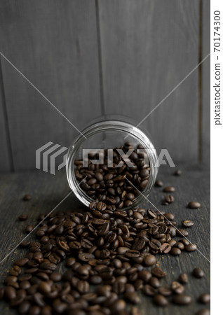 Roasted fresh arabica coffee beans scattered on a table from a little jar on a wooden table. Fresh coffee beans. Roasted fresh arabica coffee beans scattered on a table from a little jar on a wooden table. Fresh coffee beans. 70174300