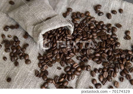 Coffee scattered from a linen bag. Fresh arabica coffee beans on linen textile. Coffee scattered from a linen bag. Fresh arabica coffee beans on linen textile. 70174329