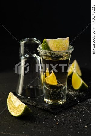 Mexican Tequila Gold in glasses with lime slices and salt. Mexican Tequila Gold in glasses with lime slices and salt. 70175223