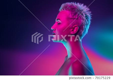 Portrait of female fashion model in neon light on dark studio background. Portrait of female fashion model in neon light on dark studio background. 70175229