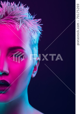 Portrait of female fashion model in neon light on dark studio background. Portrait of female fashion model in neon light on dark studio background. 70175269