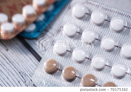 birth control pills on wooden background, close up  70175382