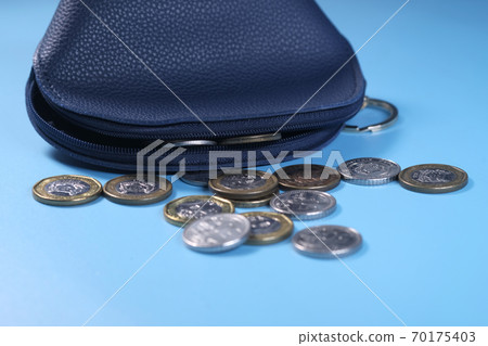 Close up of coins in a small leather bag on blue background Close up of coins in a small leather bag on blue background 70175403