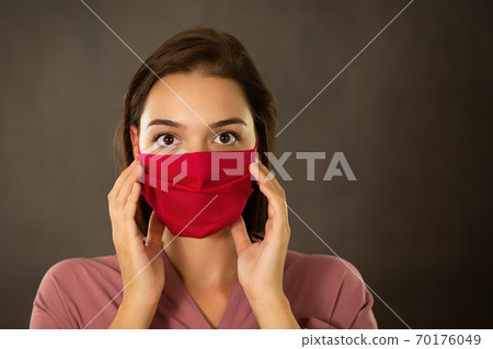 Frightened woman touching her pink face mask with fingers Frightened woman touching her pink face mask with fingers 70176049