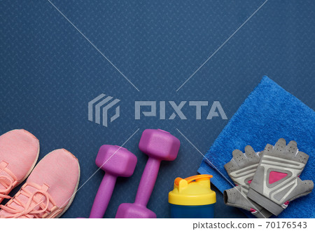 pair of purple dumbbells, sports gloves and pink gym shoes on a blue neoprene mat pair of purple dumbbells, sports gloves and pink gym shoes on a blue neoprene mat 70176543