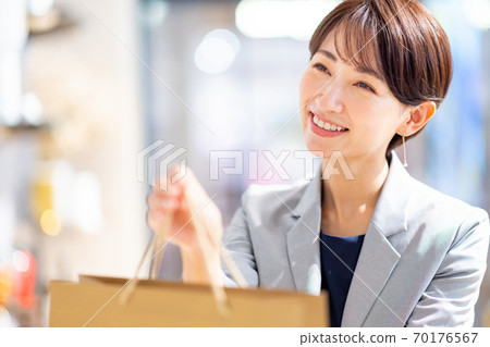 Female clerk handing over a paper bag Photo cooperation: g GIFT AND LIFE STYLE 70176567