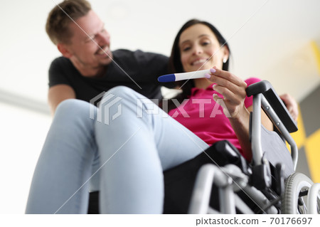 Disabled woman in wheelchair is holding test with her husband at home. 70176697