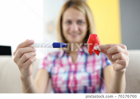 Test and red ribbon in hands of smiling woman closeup Test and red ribbon in hands of smiling woman closeup 70176700