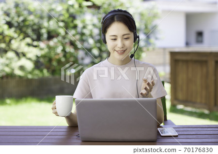 Young woman doing telework in the garden Young woman doing telework in the garden 70176830